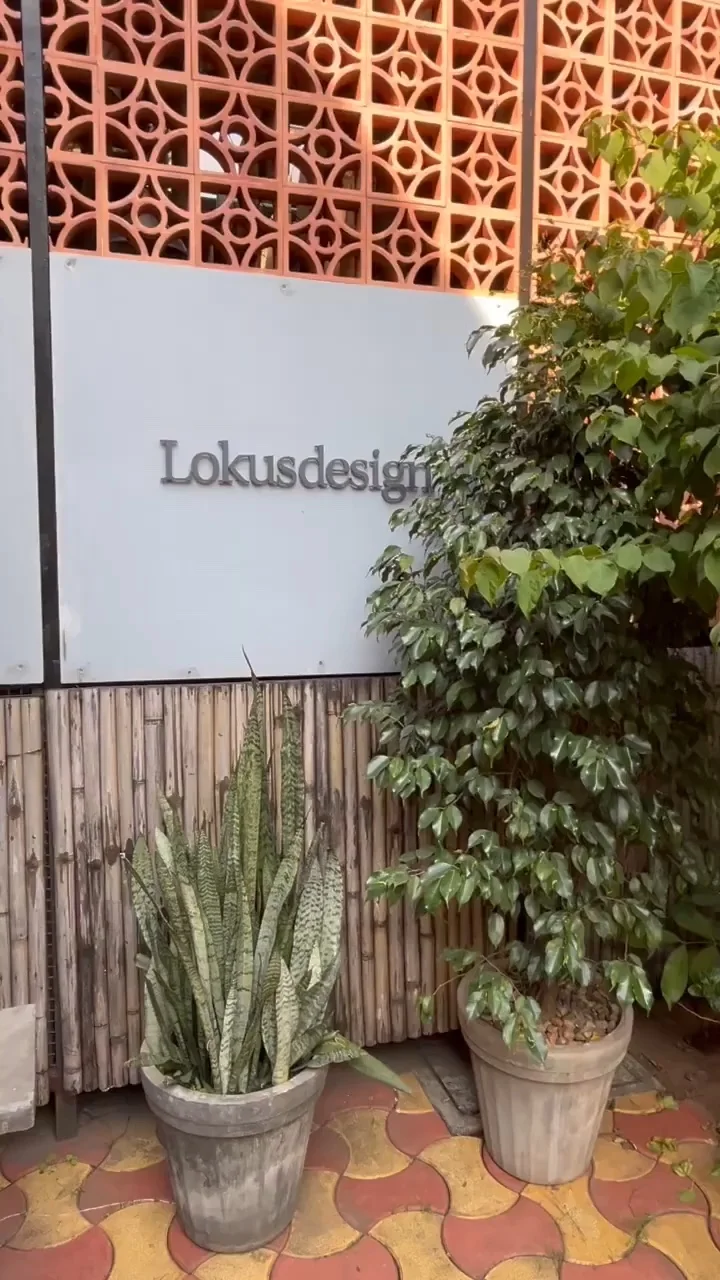 The Lokusdesign studio entrance with plants in front of a perforated terracotta wall
